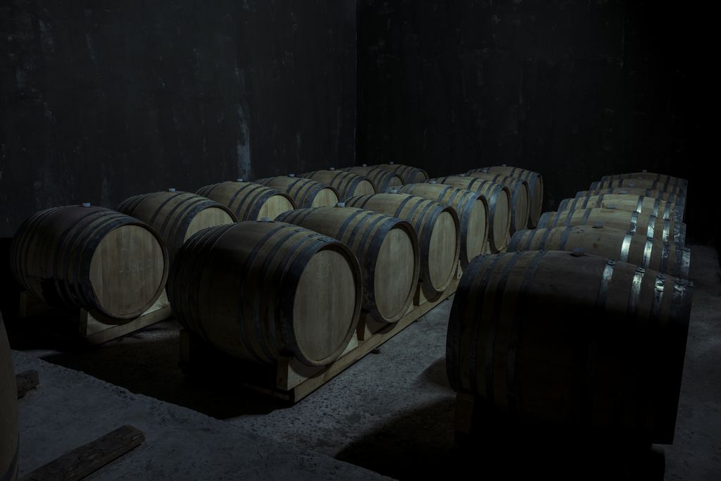 Rows of oak barrels lying in a dark winery cellar