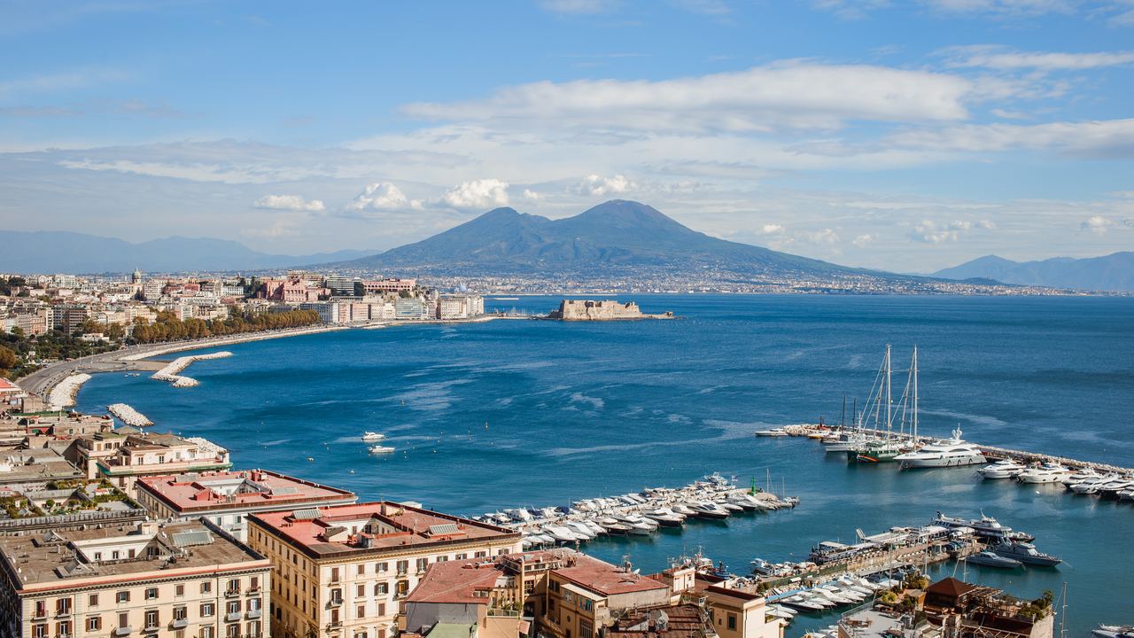 View across the Bay of Naples to Mount Vesuvius, with boats in the harbour and the city along the shore