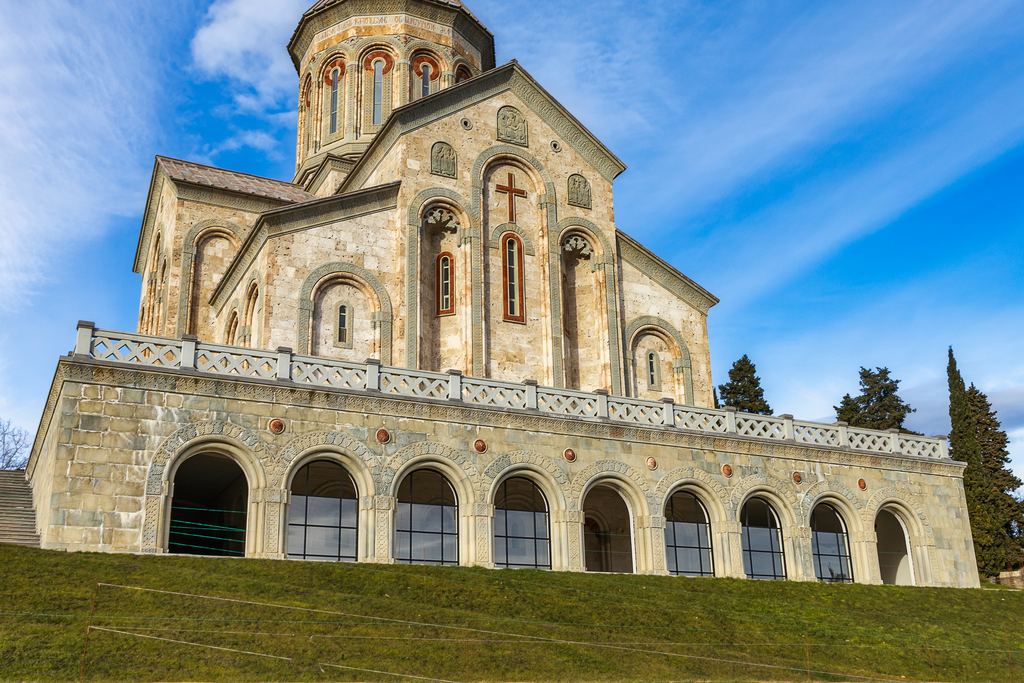 Stone church of Bodbe Monastery near Sighnaghi seen from the lawn below, blue sky behind