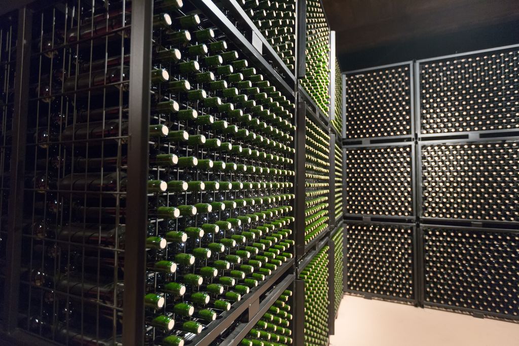 Rows of wine bottles ageing on metal racks in a winery cellar
