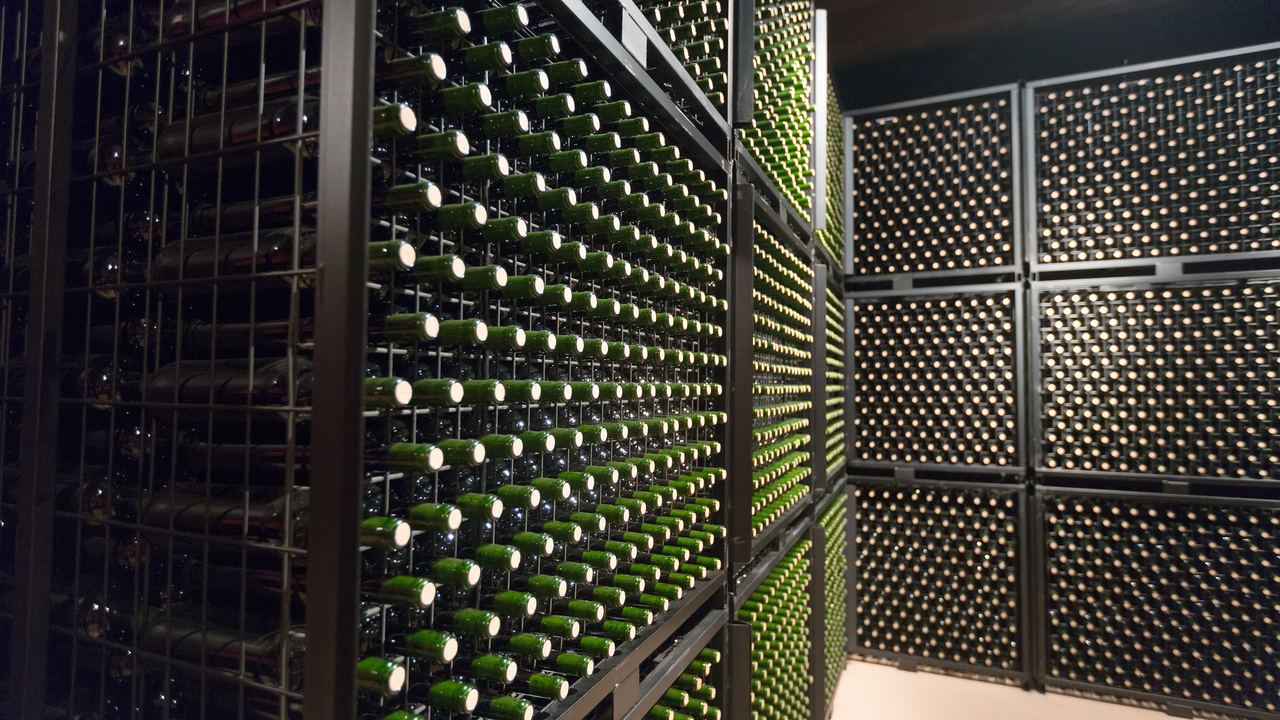 Rows of wine bottles ageing on metal racks in a winery cellar