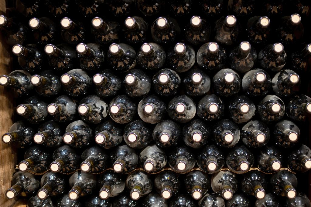 Wine bottles stacked with their necks facing out in a cellar