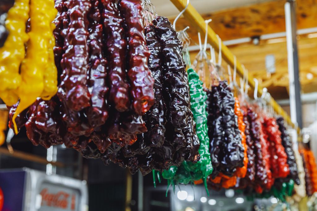 Strings of churchkhela in red, green, yellow and brown hanging at a market stall