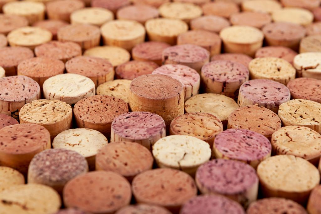 Close-up of a bed of used wine corks, some stained red and purple from the wine