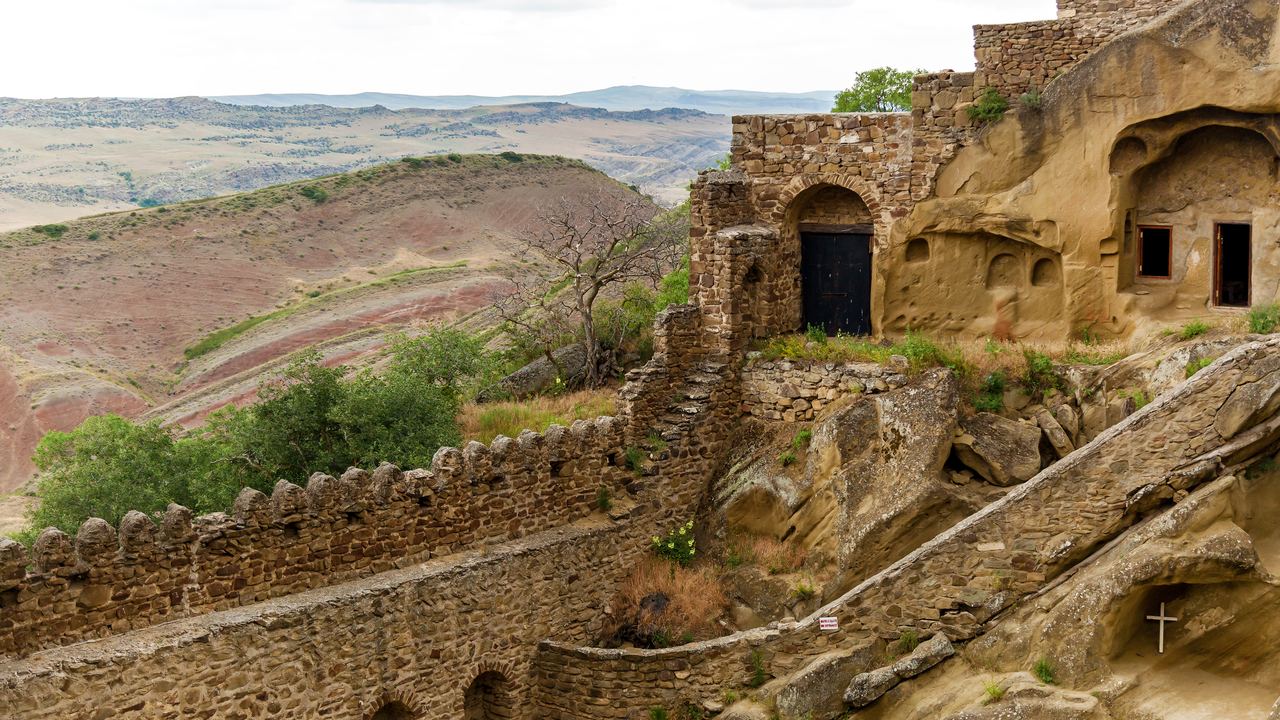 Stone walls and cave cells of David Gareja monastery on a dry hillside in eastern Georgia
