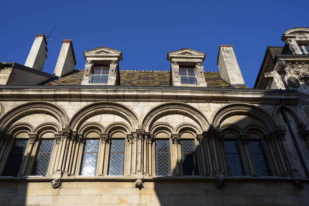 Stone façade with dormer windows and a glazed tile roof in Dijon
