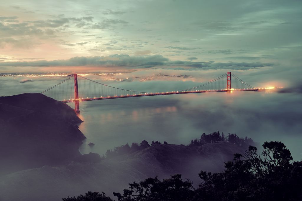 The Golden Gate Bridge lit at dusk above low fog, San Francisco Bay