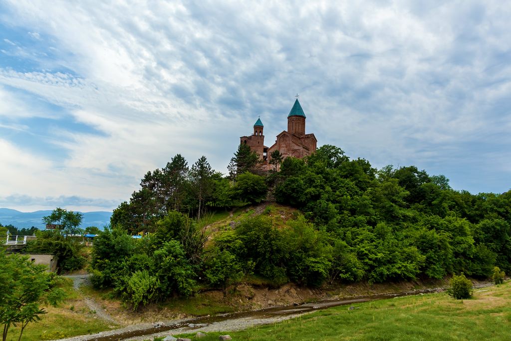 Fortified brick church of Gremi on a wooded hill under a cloudy sky in Kakheti, Georgia
