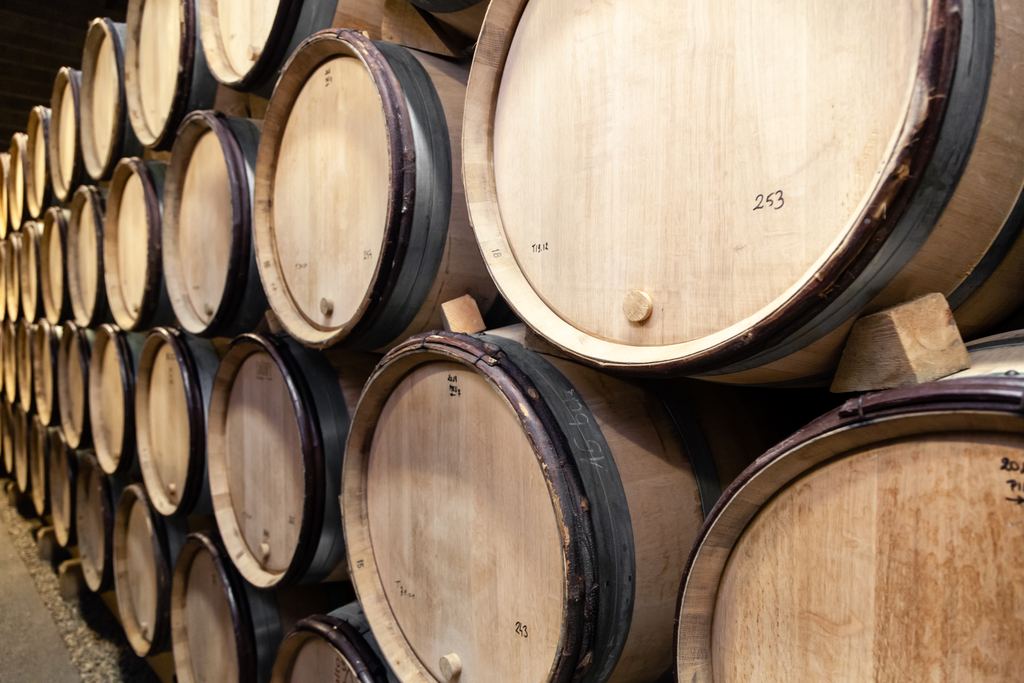 Rows of oak wine barrels stacked in a Burgundy winery cellar