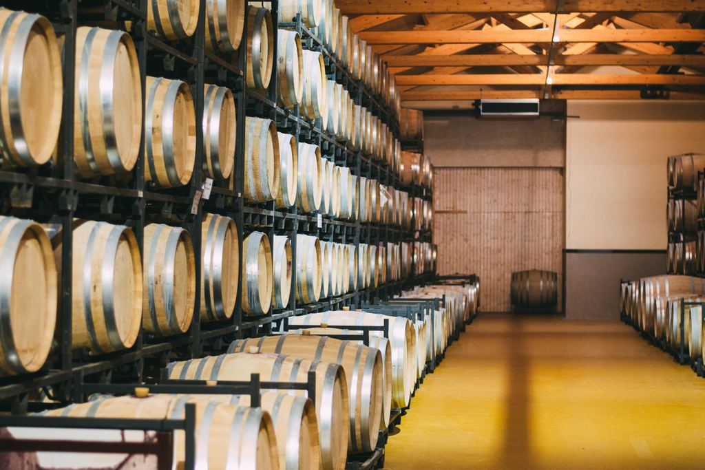 Rows of oak barrels stacked in a winery cellar