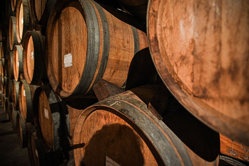 Oak wine barrels stacked on their sides in a winery cellar