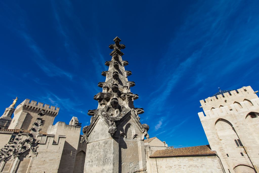 Gothic pinnacle and towers of the Palais des Papes in Avignon against a blue sky