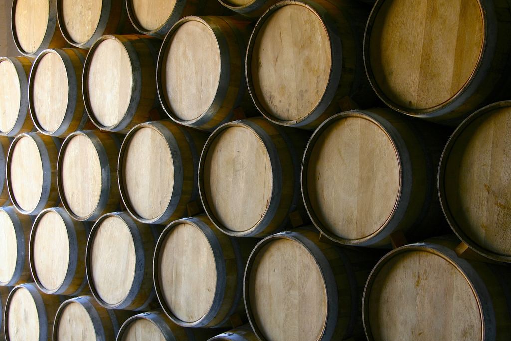 Rows of oak wine barrels stacked in a winery cellar