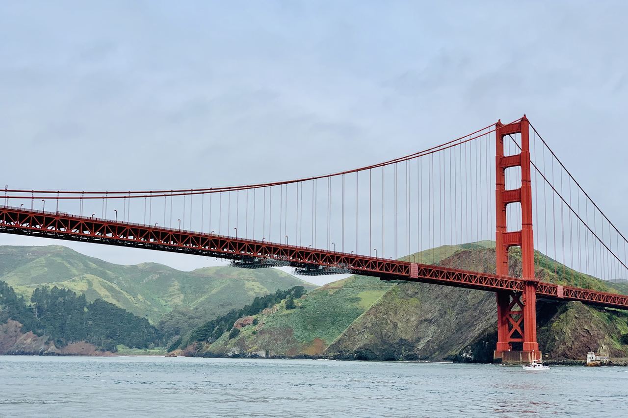 Red suspension bridge and green headlands seen from the water, the Golden Gate Bridge in San Francisco