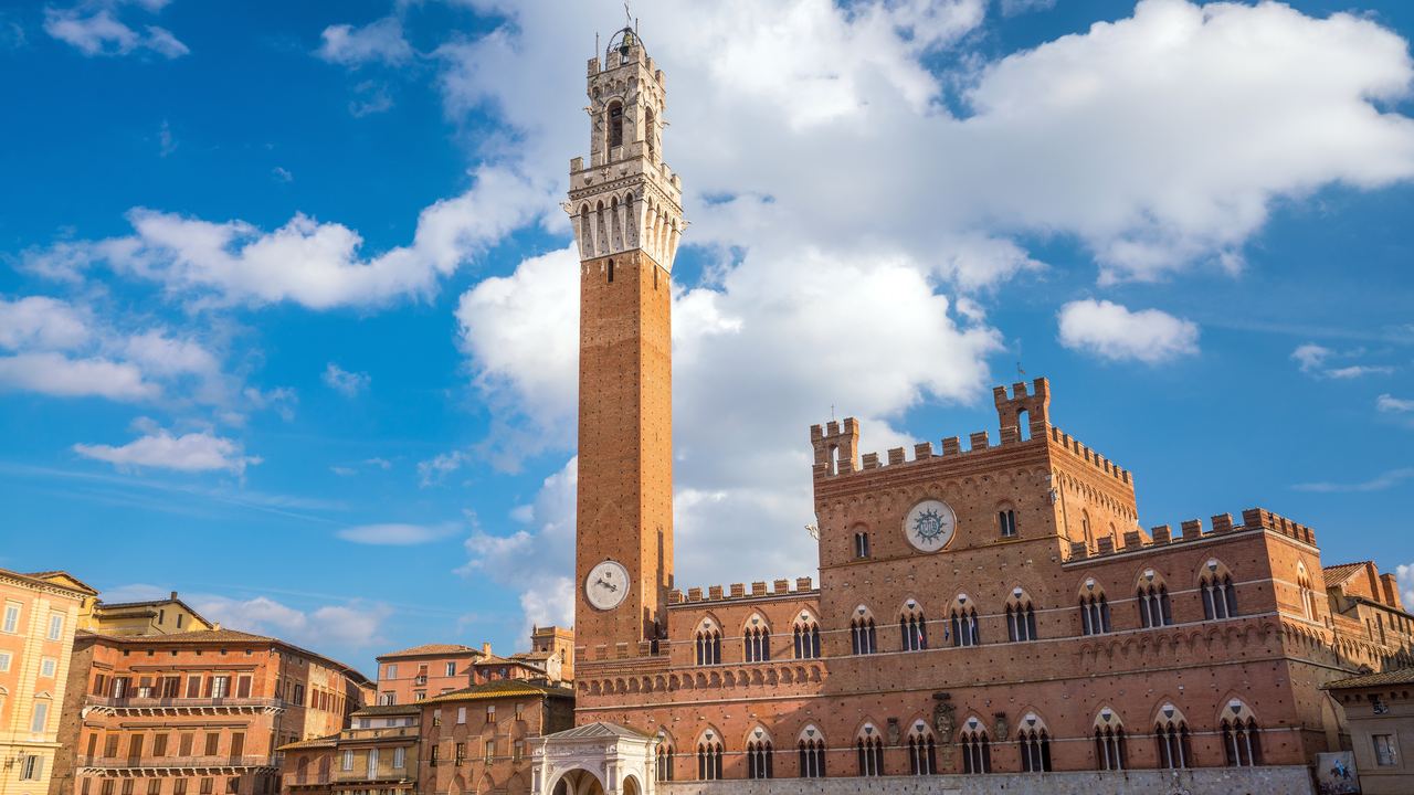 Torre del Mangia and Palazzo Pubblico on Piazza del Campo in Siena under a blue sky