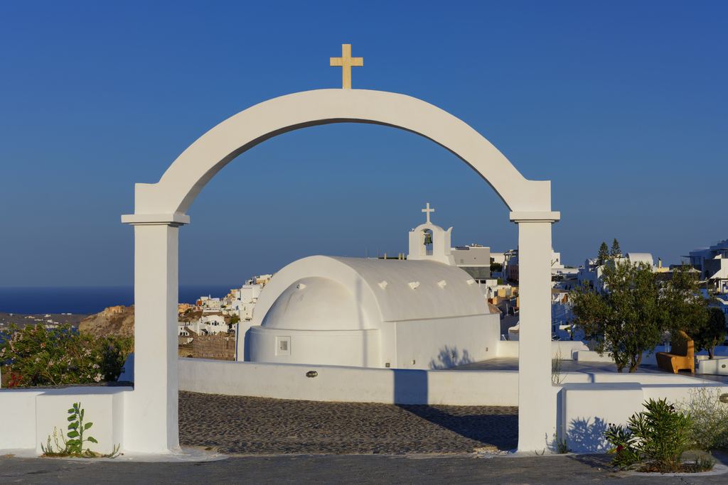 Whitewashed arch and domed chapel in Oia under a deep blue sky, Santorini, Greece