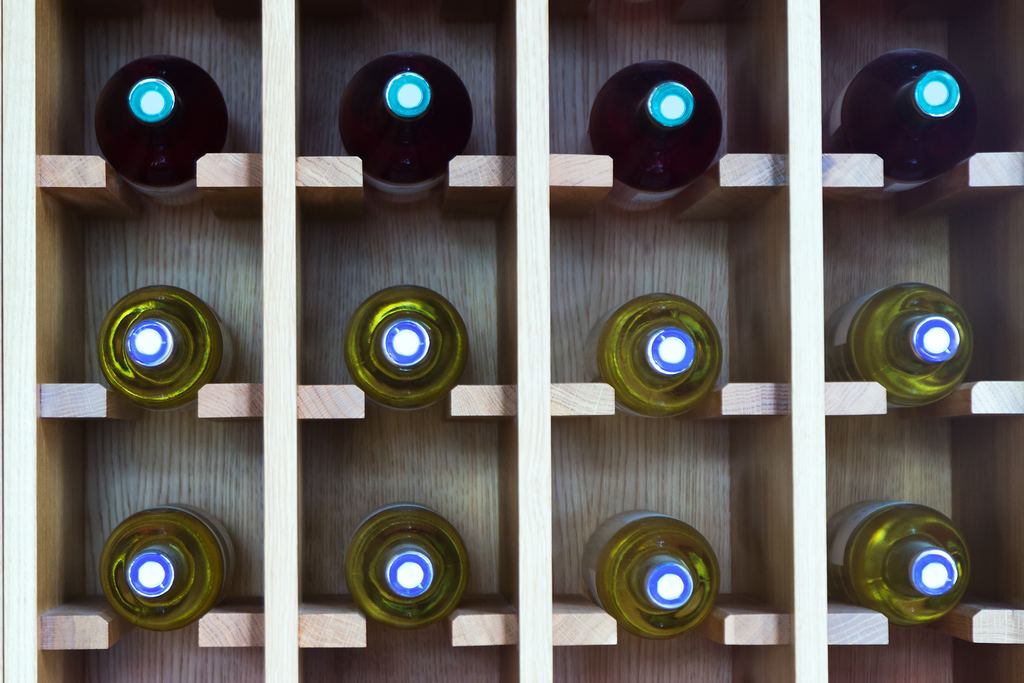 Rows of wine bottles lying on a wooden rack, seen from above