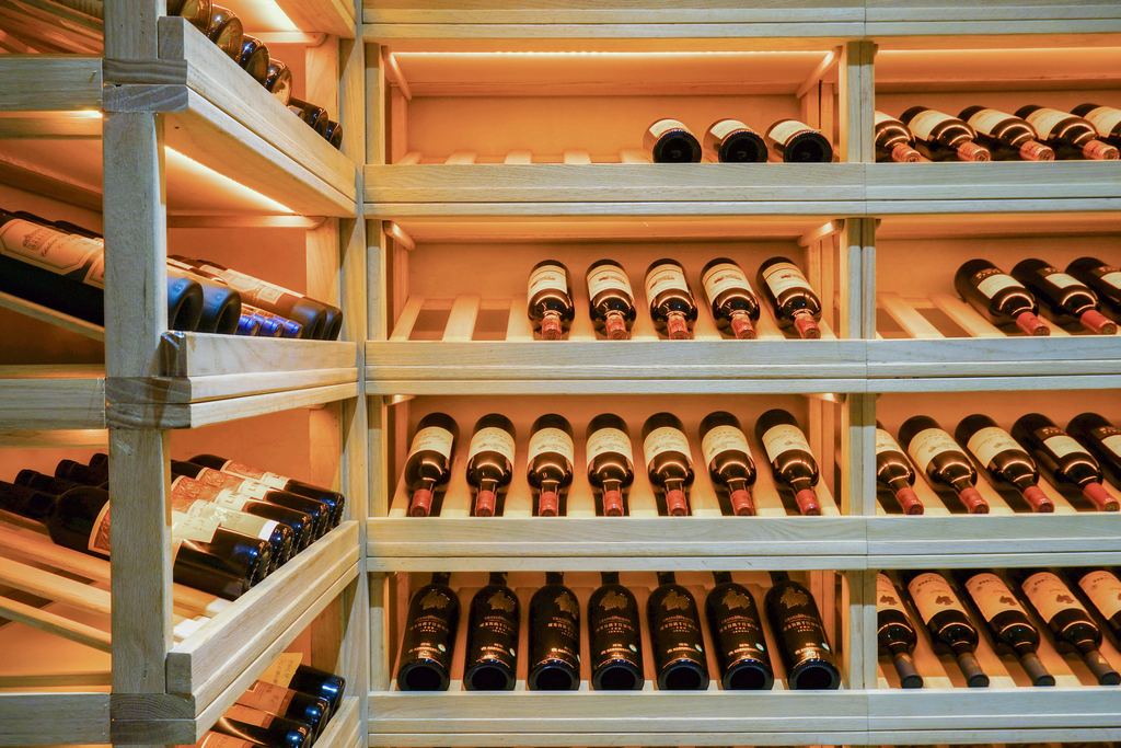 Red wine bottles lying on lit wooden shelves in a wine shop